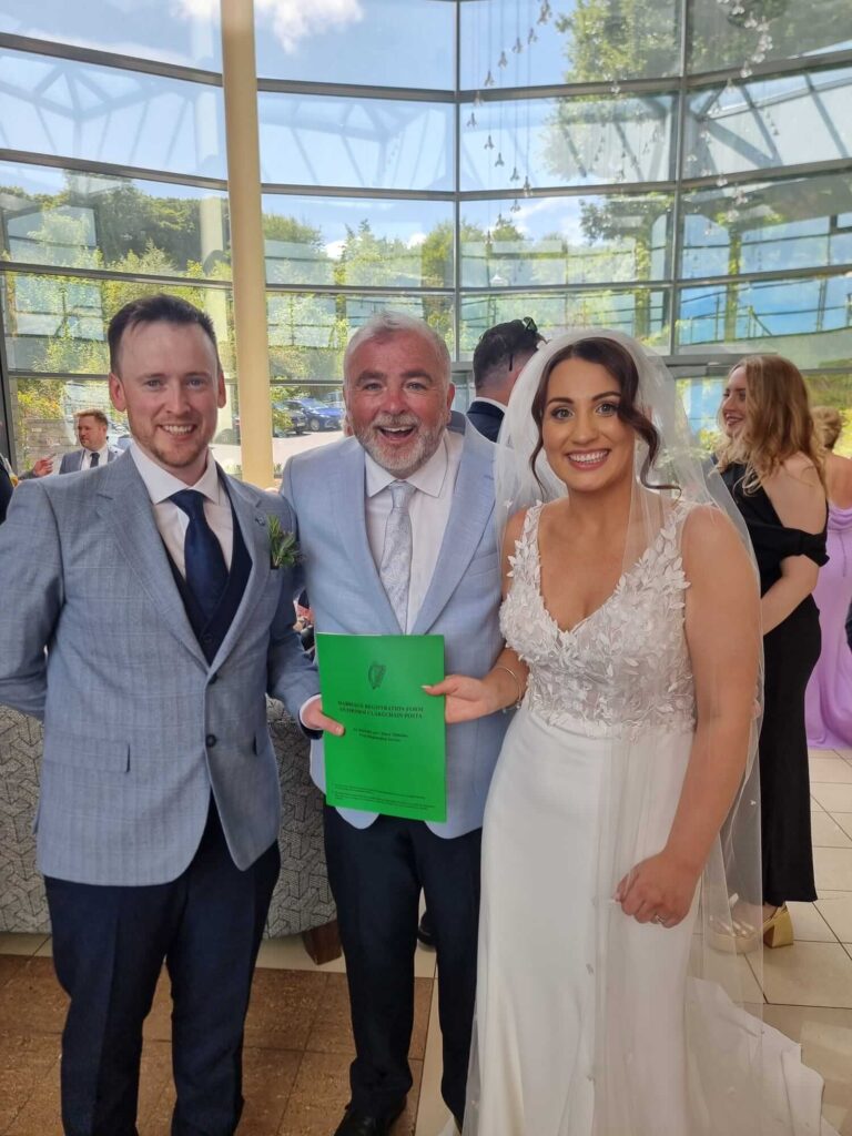 Celebrant with a happy couple holding their Irish marriage certificate at a wedding ceremony in Cork.