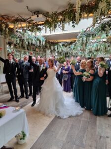 Happy newlyweds recessing down the aisle at a Maryborough Hotel wedding, surrounded by celebrating guests and lush greenery decor.