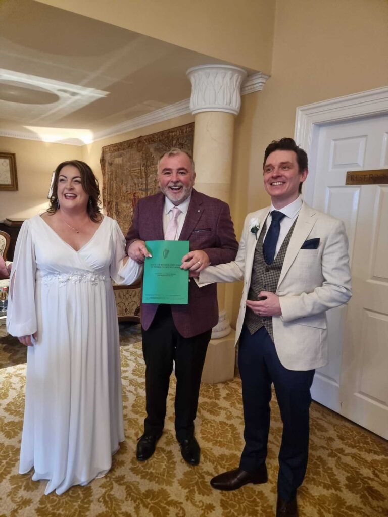 Bride, groom, and celebrant posing with their marriage certificate at Hayfield Manor.